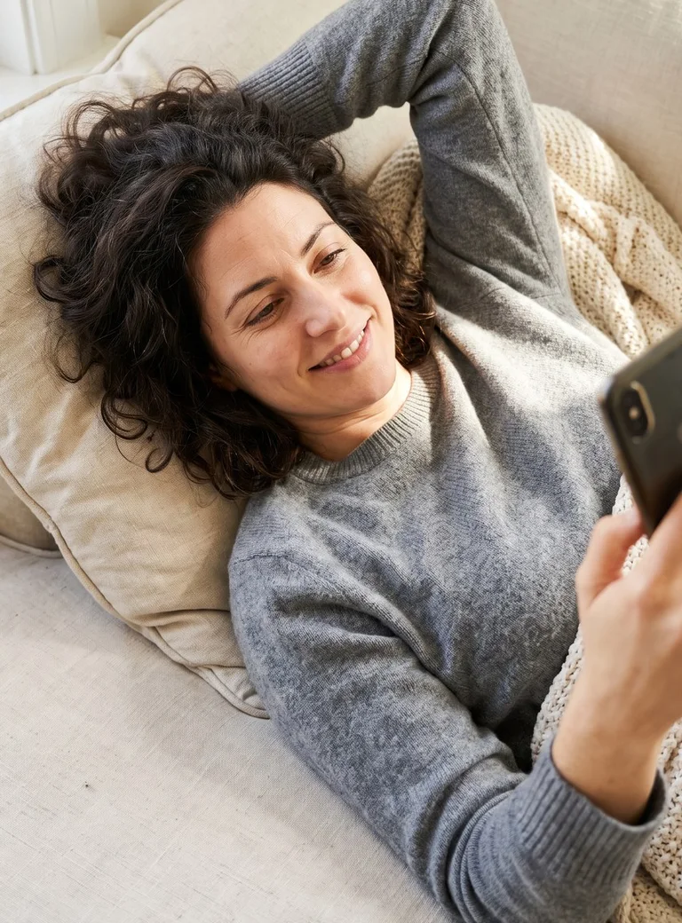 A woman relaxing on a sofa with her phone